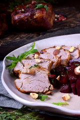 Roast pork meat cut into slices served with stewed beet roots on the white plate