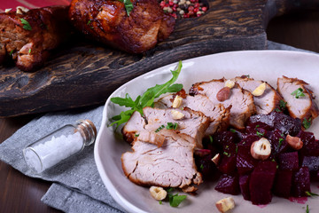 Roast pork meat cut into slices served with stewed beet roots on the white plate