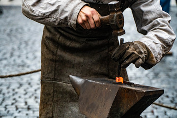 Blacksmith working on metal on anvil at forge