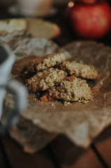 Oatmeal cookies on parchment paper on a background of apple and candles