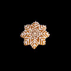 Gingerbread cookies in the shape of snowflakes, covered with white icing on a black background.