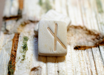 Wooden rune Nauthiz close-up on a wooden background. Soft focus