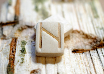 Wooden rune Hagalz close-up on a wooden background. Soft focus