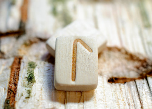 Wooden rune Laguz close-up on a wooden background. Soft focus
