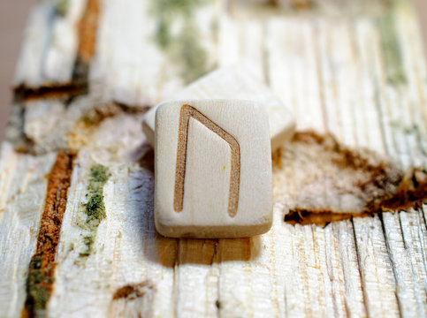 Wooden rune Uruz close-up on a wooden background. Soft focus