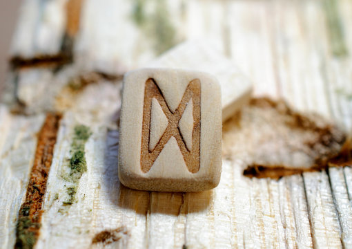 Wooden rune Dagaz close-up on a wooden background. Soft focus