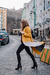woman in yellow coat walking on city street