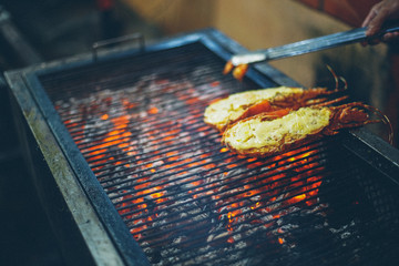 Street food at night in Vietnam. Seafood grilling on ember stove. Delicous color of BBQ shrimp or prawn grilled.