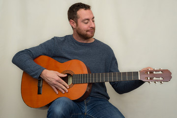 Smiling musician tuning a spanish guitar.