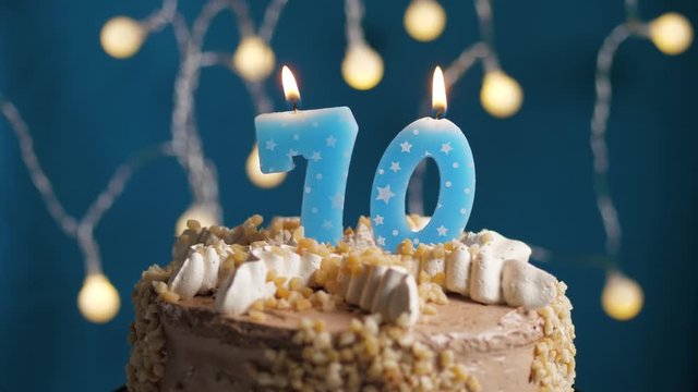 Birthday cake with 70 number candle on blue backgraund. Candles blow out. Slow motion and close-up view