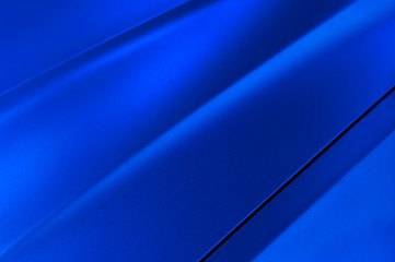 Surface of blue sport sedan car metal hood, part of vehicle bodywork, steel gradient line pattern, selective focus