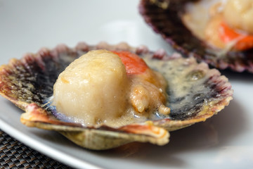 Baked scallops with cheese and spicy sauce. Delicate clam is a real pleasure. Romantic dinner at a Spanish fish restaurant. Mallorca Island, Spain.