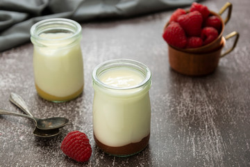 Fresh yogurt in glass jar with fruits on dark background. Healthy food, milk diary.