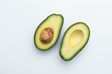 Avocados cut in halves. White Top view. Healthy food.