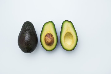 Avocados cut in halves. White background. Top view. Healthy food.
