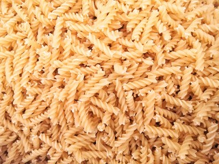 Pile of spiral pasta in the sack with selective focus. Spiral pasta background. Uncooked Italian pasta for healthy dietary dishes. 