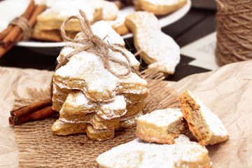 Homemade egg-free vegetarian cookies sprinkled with powdered sugar. Festive cookies on crumpled paper in the shape of a Christmas tree, a heart, a butterfly and a bird.