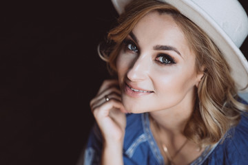 Beautiful stylish elegant blonde woman in ethnic clothes in an embroidered shirt in a white hat in the interior in grunge style. Ukrainian national clothes.