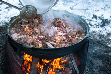 Cooking meat on fire in a large cauldron. A traditional dish.