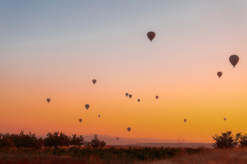 Many colorful balloons fly over the mountains - a panorama of Cappadocia at dawn. Goreme Valley Landscape in Cappadocia - Background for your travel concept in Turkey.
