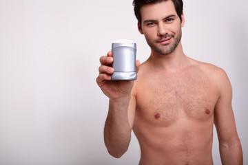 Pretty sexy man holds gray deodorant in hand