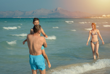 Family of three spending time on beach on summer vacations.