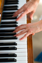 Fototapeta premium Beautiful female hands play the piano, close-up