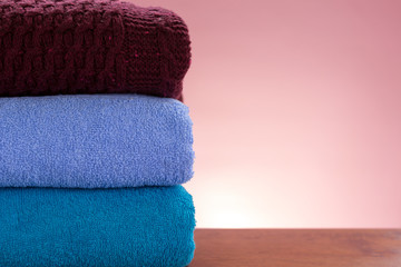 Stack of clean clothes over colored background with copy space. Close up and selective focus. Household concept