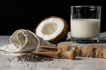  Glass of coconut milk near uncovered coconut and chia seeds