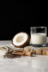  Glass of coconut milk near uncovered coconut and chia seeds