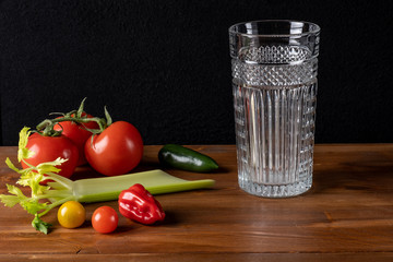 Fresh organic tomato juice decorated with raw tomatoes, leaves on a dark rustic wooden background. Healthy diet nutrition concept. 