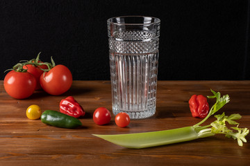 Fresh organic tomato juice decorated with raw tomatoes, leaves on a dark rustic wooden background. Healthy diet nutrition concept. 
