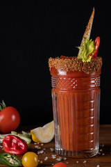 Fresh organic tomato juice decorated with raw tomatoes, leaves on a dark rustic wooden background. Healthy diet nutrition concept. 