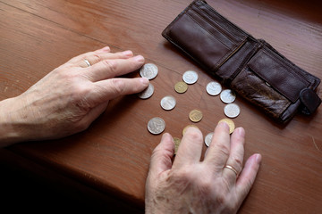 Hands of an old man and counting money, coins. The concept of poverty, low income, austerity in old age.