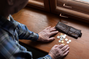 Hands of an old man and counting money, coins. The concept of poverty, low income, austerity in old...