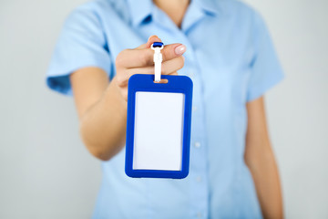Female hand showing blank white bagde on grey background