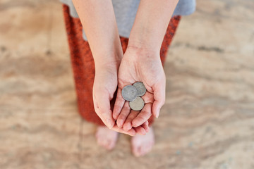 Homeless Poor girl asks for money. Outstretched hands with a dime