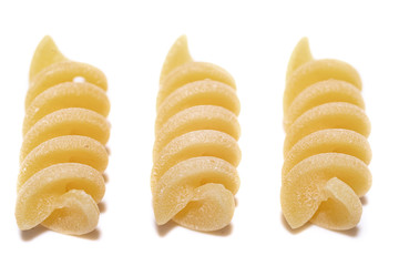 Italian raw Pasta Fusilli three pieces laid out in a row. Close up.white background.