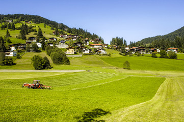 Traktor am Feld, Dorf im Hintergrund, Österreich, Tirol, Wildsc © visualpower