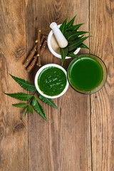 Medicinal Neem leaves in mortar and pestle with neem paste, juice and twigs on wooden background