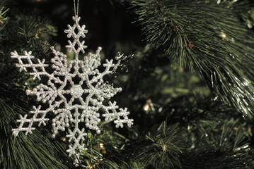 A star or snowflake ornament hangs from a Christmas tree