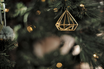Geometric Christmas ornaments hang from a Christmas tree