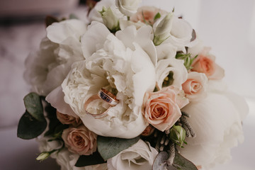 2 golden rings on wedding bouquet with beautiful roses and pions. Wedding day. Wedding preparation
