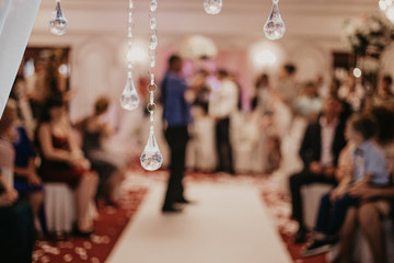 Blur Golden bokeh from beautiful crystal. Wedding arch decoration close-up. Pendants made of crystals close-up. Lots of guest and people on blur background. Horizontal