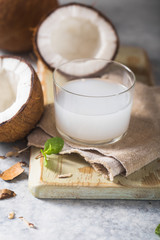 Cracked fresh coconut, milk  and slice nut on concrete background, space for text Food ingredients, healthy lifestyle, paradise concept