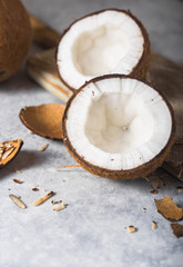 Fototapeta premium Cracked fresh coconut, milk and slice nut on concrete background, space for text Food ingredients, healthy lifestyle, paradise concept