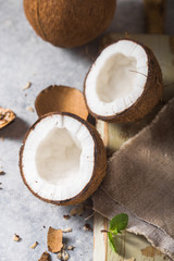 Obraz na płótnie Canvas Cracked fresh coconut, milk and slice nut on concrete background, space for text Food ingredients, healthy lifestyle, paradise concept