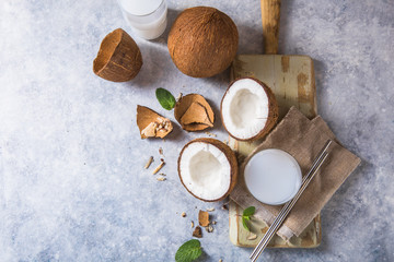 Fototapeta na wymiar Cracked fresh coconut, milk and slice nut on concrete background, space for text Food ingredients, healthy lifestyle, paradise concept