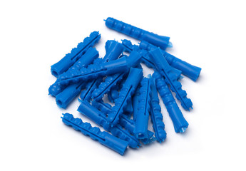 Pile of brass screws and blue plastic dowels lying on flat surface