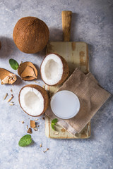 Cracked fresh coconut, milk  and slice nut on concrete background, space for text Food ingredients, healthy lifestyle, paradise concept